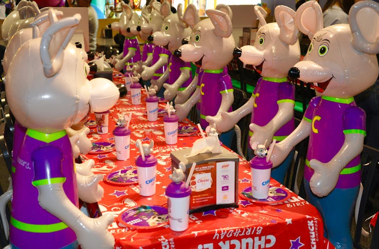 Lots of Chuck E. Cheese mice at a table.