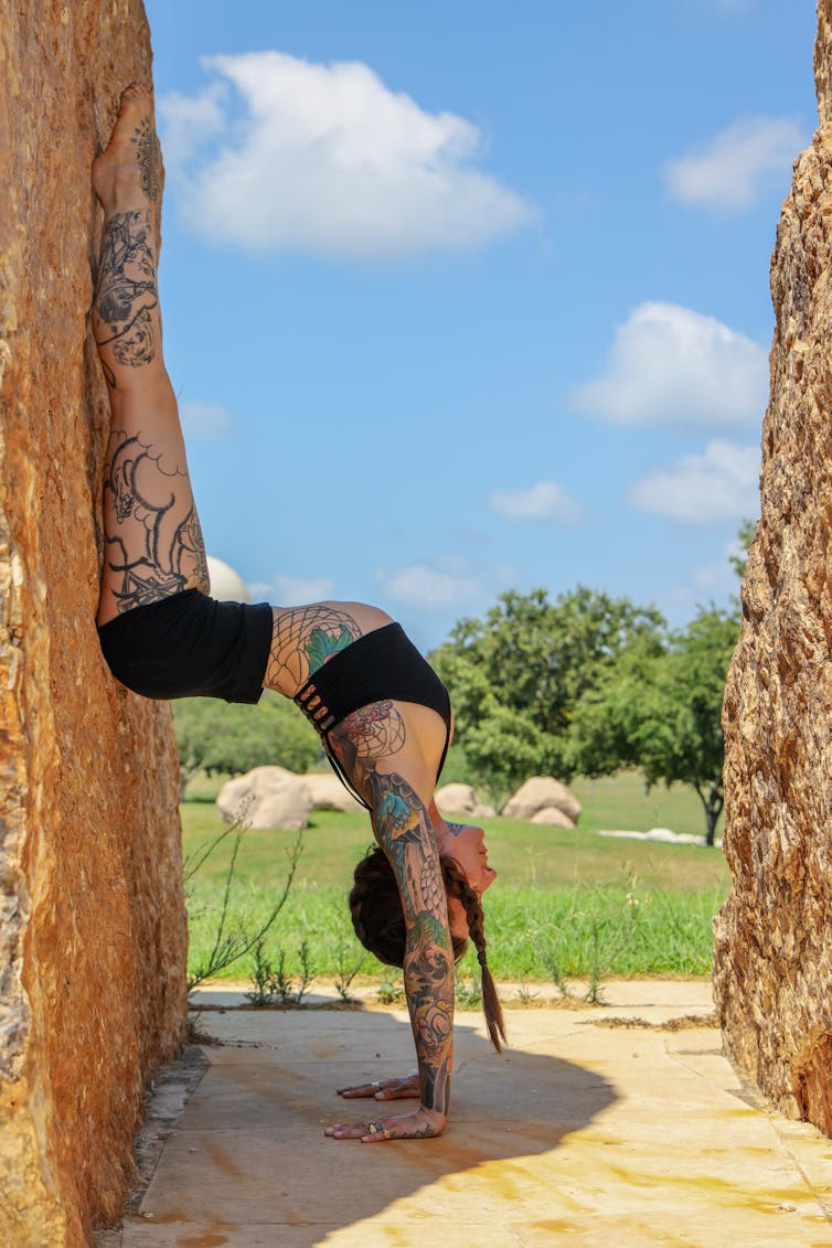 Tattooed girl doing a handstand against a wall