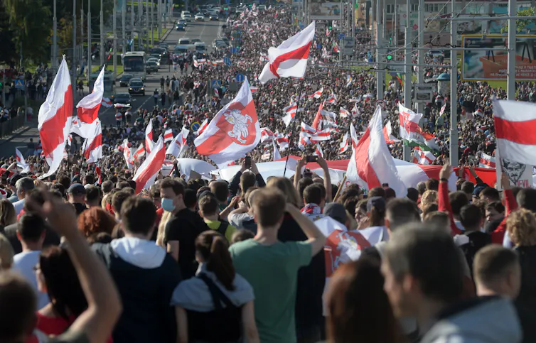 Large crowd of Belarusian protesters waving flags.