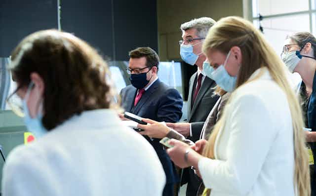 Journalists wearing masks in a media scrum. 