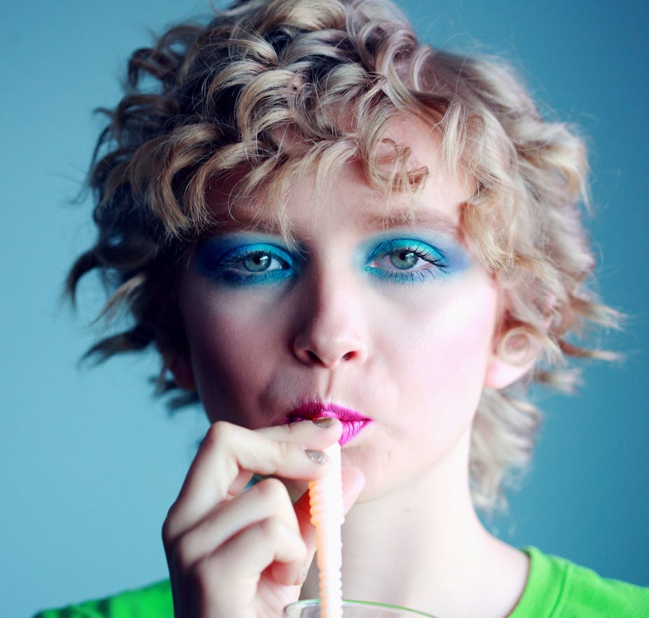 Woman with blue eye shadow drinking from straw 