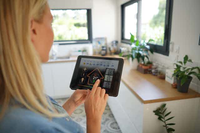 A woman looks at a smart energy system on an iPad in her home.