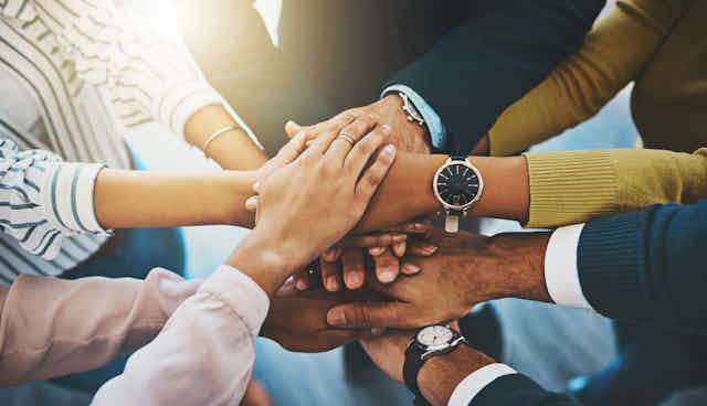 Closeup shot of a group of businesspeople joining their hands together in a huddle.