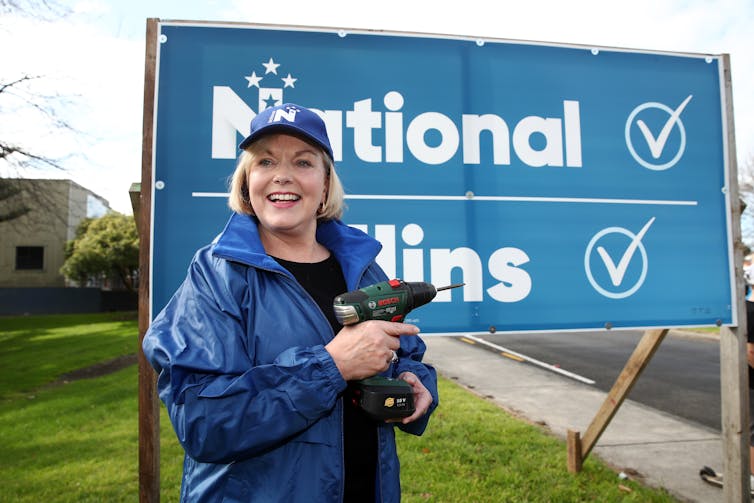 woman holding electric drill in front of advertising billboard