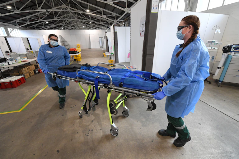 Two ambulance volunteers push a stretcher