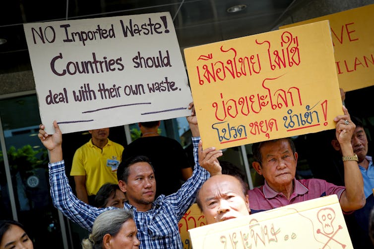 Man holds sign saying 'No imported waste! Countries should deal with their own waste'