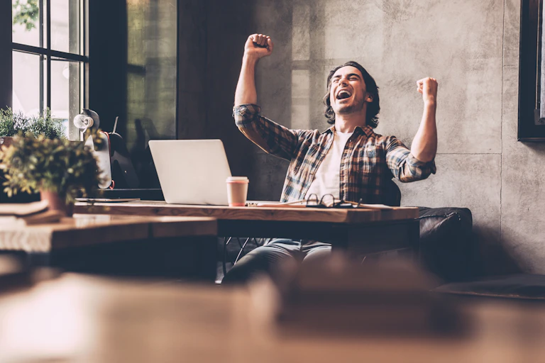Happy man cheering at his work station.