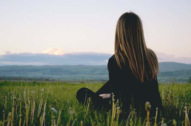 Woman sitting alone in field.