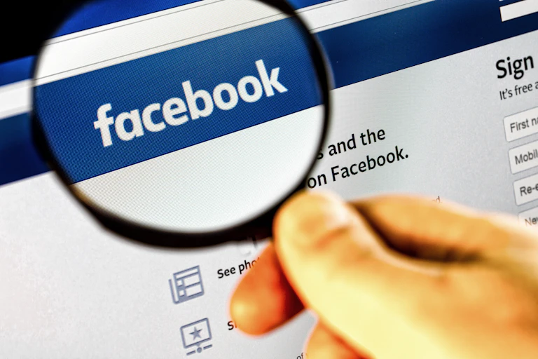 Lupa ampliando el logotipo de Facebook.