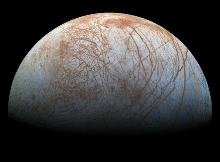 Jupiter's white with brown streaks moon Europa in space,