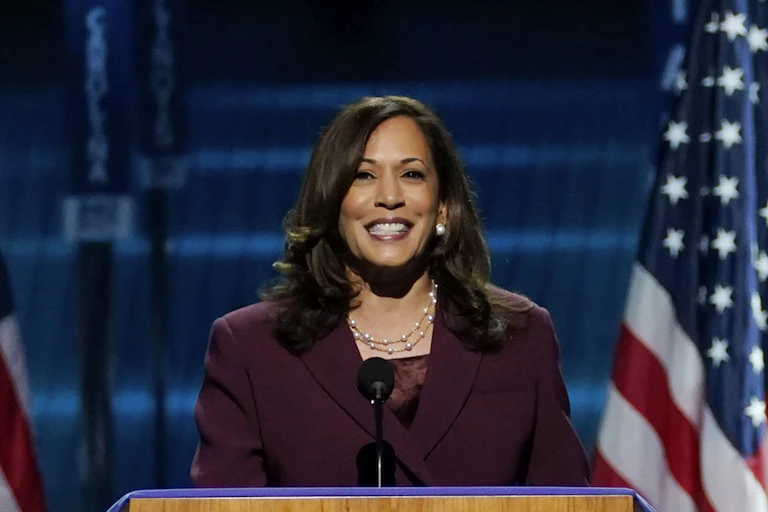 Kamala Harris speaks from behind a podium flanked by American flags.