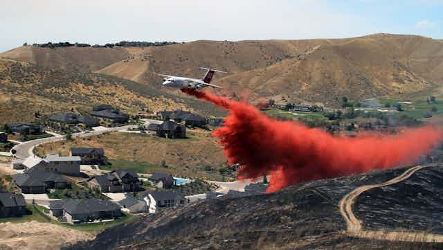 Tanker dropping fire retardant on scorched hillside in suburban Boise