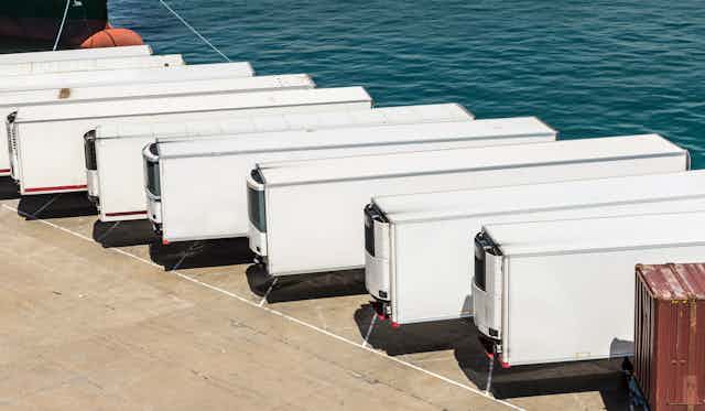 A line of freezer trucks parked on a dock.