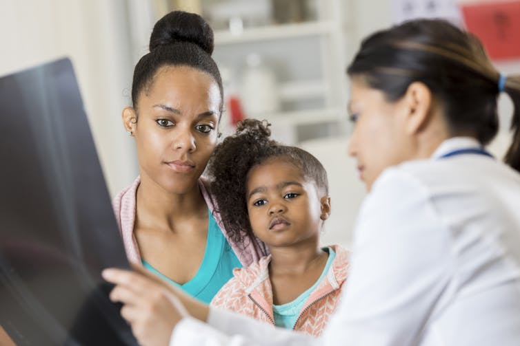 Woman and child look at X-ray with pediatrician