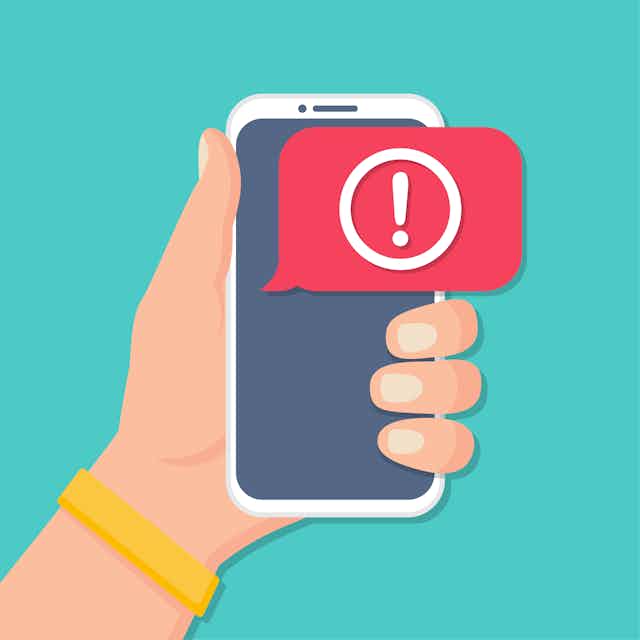 A hand holding a phone with an alert.