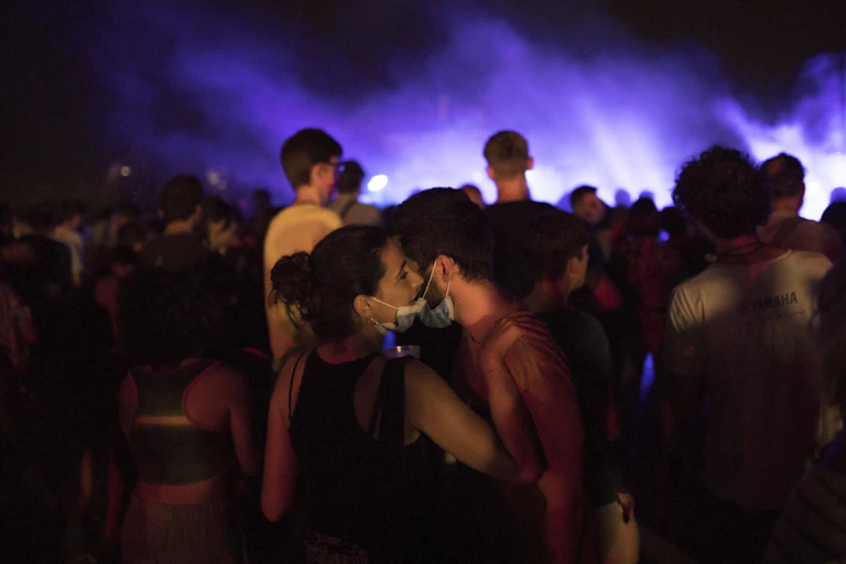 A woman and man in face masks stand close at a party.