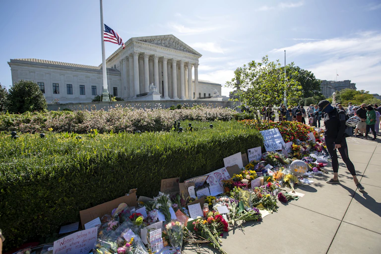 The Supreme Court with the US flag at half staff and flowers in front