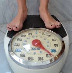 A woman's feet standing on a scale that reads about 51 kilograms.