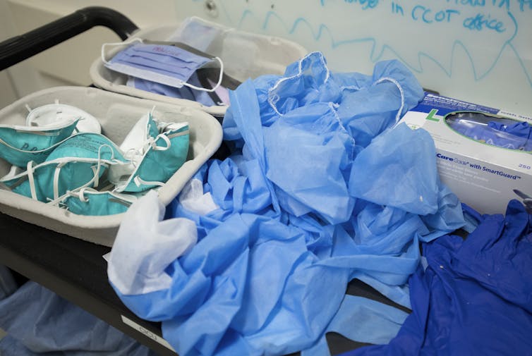 A cart holding PPE, including surgical masks, N95 masks, gloves, gowns and caps