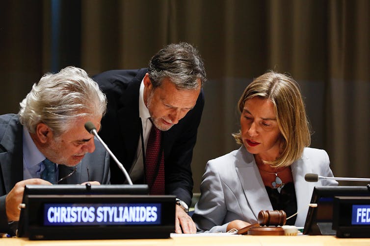 Diplomats discussing document at UN general assembly.