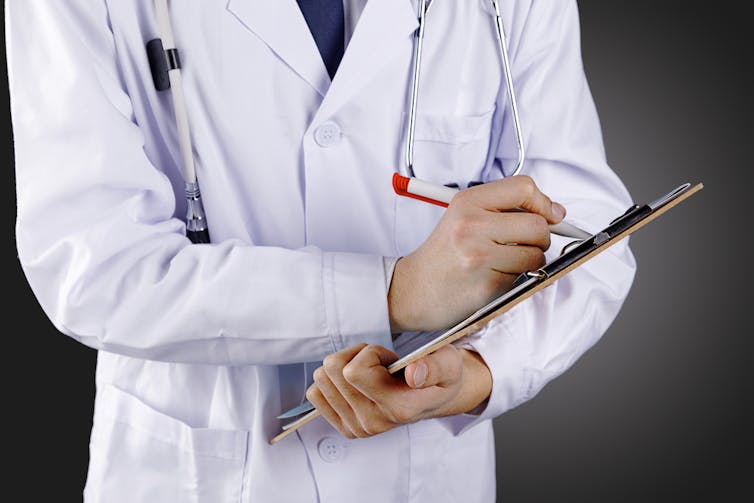 Researcher in a white lab coat writing on a clipboard.