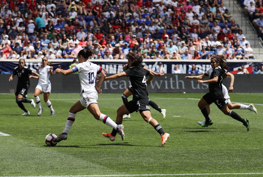 Female footballers face off during a match.