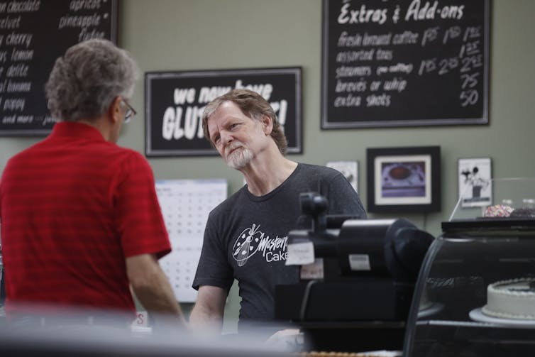 A man behind a counter waits on a customer.