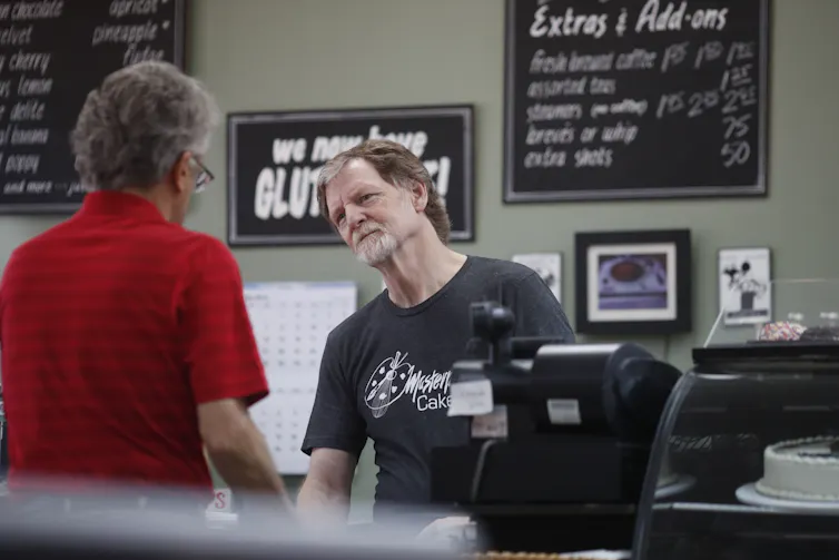 A man behind a counter waits on a customer.