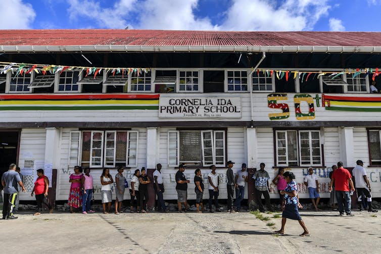 Line of people standing outside a colorfully painted school