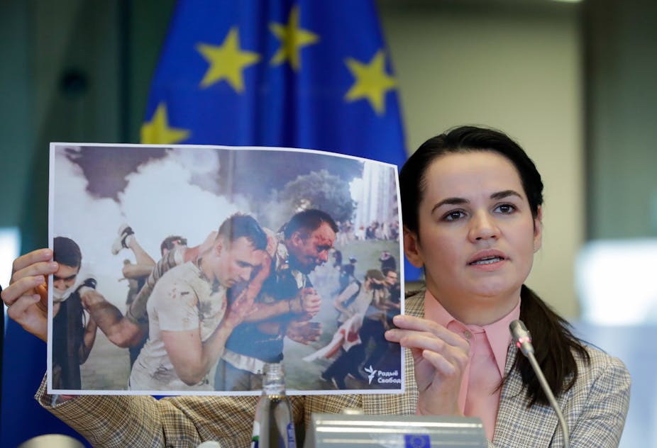 Svetlana Tsikhanouskaya holds up photo of men being attacked.