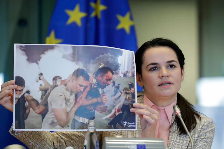 Svetlana Tsikhanouskaya holds up photo of men being attacked.