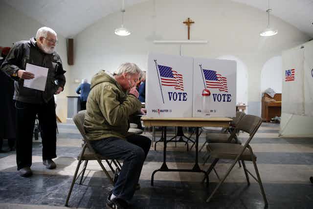 A man casts his vote at a desk in a church in New Hampshire.