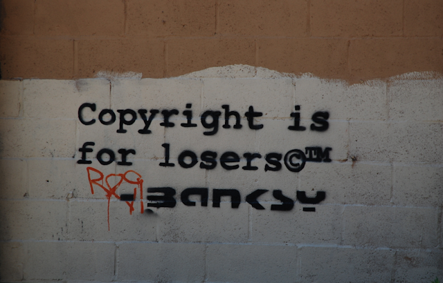 Wall at 244 Water Street NYC showing Banksy graffiti that says "Copyright is for losers"."