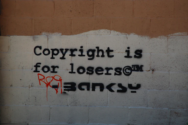 Wall at 244 Water Street NYC showing Banksy graffiti that says "Copyright is for losers"."