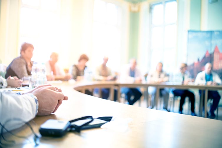 A picture of people sitting around a desk.