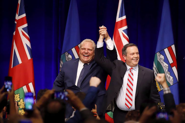 Jason Kenney and Doug Ford clasp raised hands