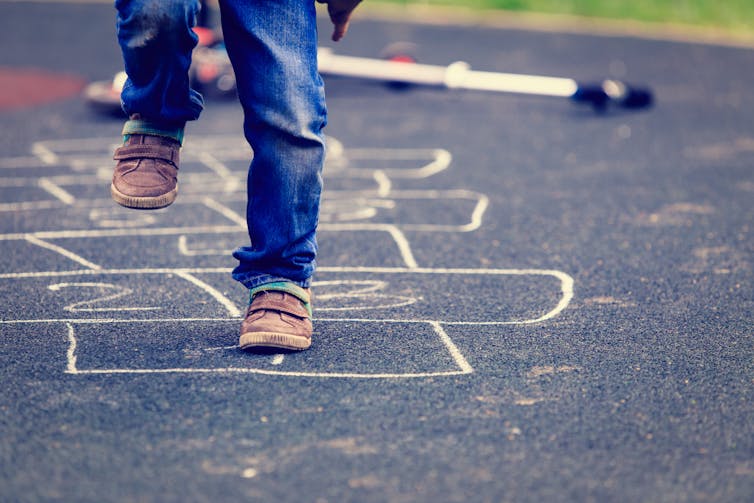 Legs and feet of child paying hopscotch.