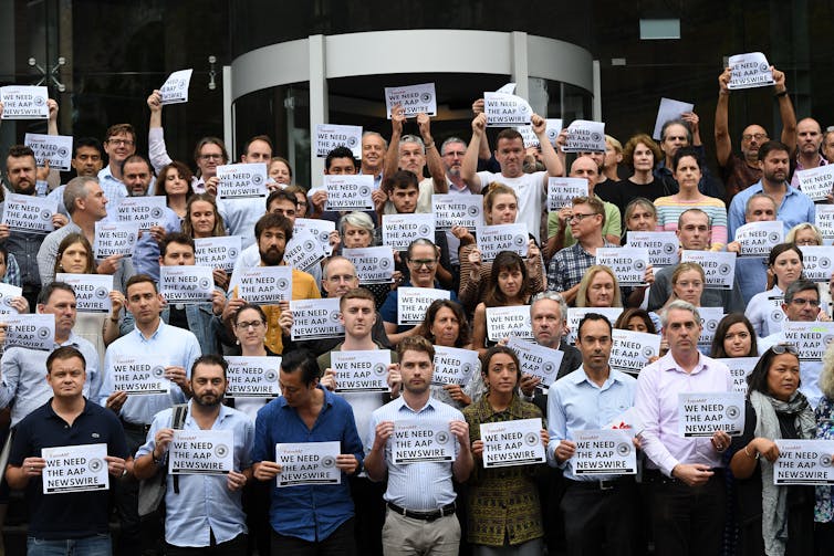 Media staff hold up signs in support of AAP employees
