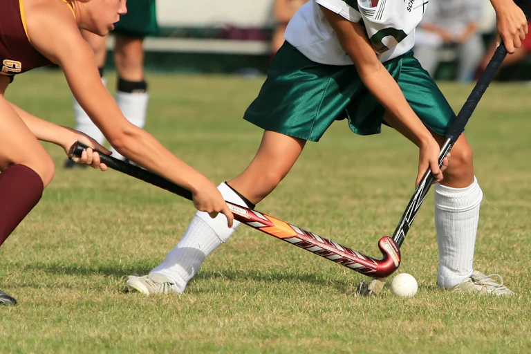 Two female school students playing hockey.
