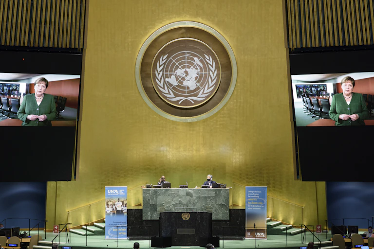 TV screens showing Angela Merkel with rows of people watching at UN.