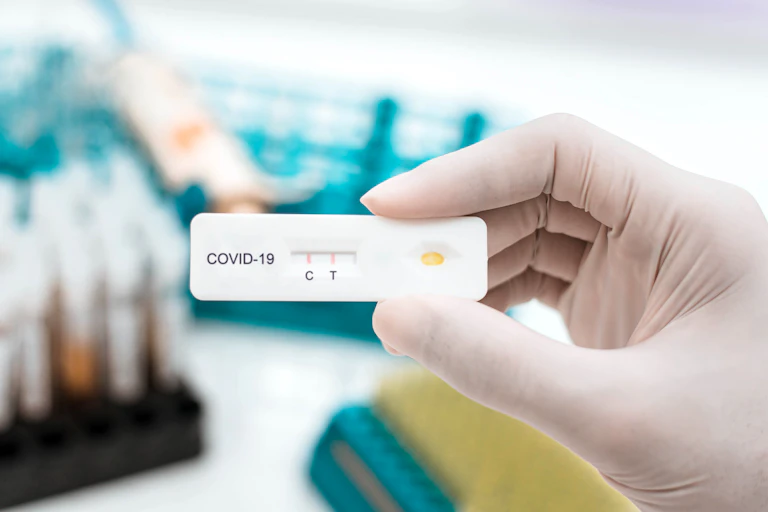 Un mano enguantada muestra un dispositivo de test de antígenos.