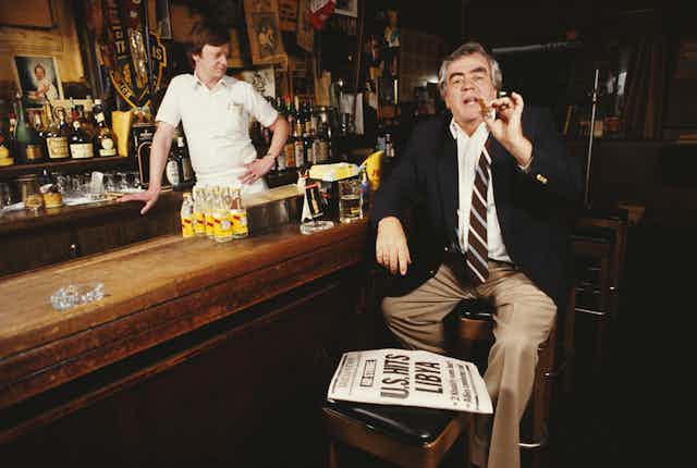 Jimmy Breslin smoking a cigar at a bar.