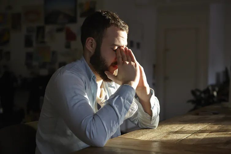 bearded man with eyes closed and hands to his face