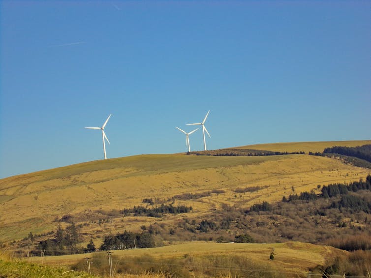 Wind turbines on a green hillside.