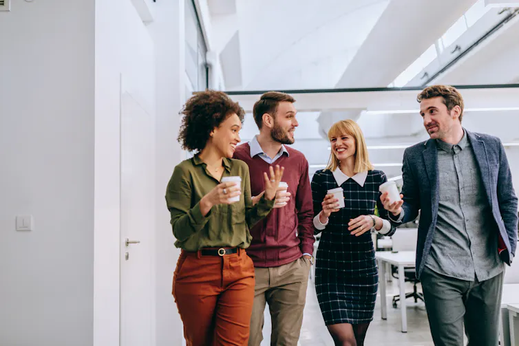 Group of co-workers walking through office and talking.