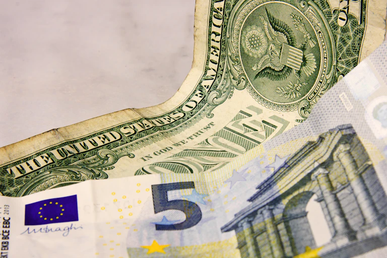 Billetes de cinco euros y de un dólar.