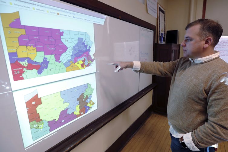 A man points at two maps of Pennsylvania congressional districts.