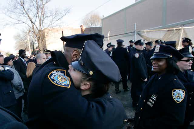A male and a female police officer hug.