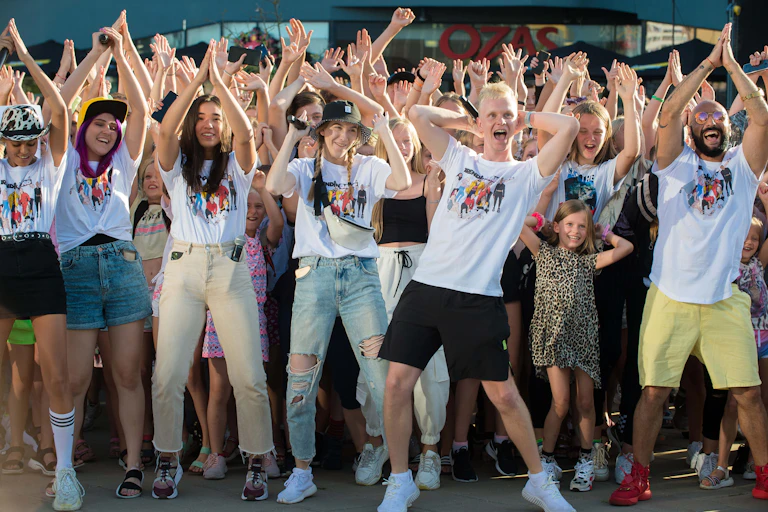A group of young people dance with their arms in the air