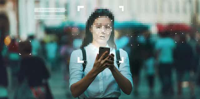 A young white woman with a pixelated face lit by her cellphone